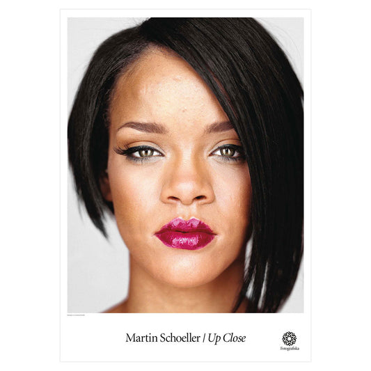 Colorful headshot of Rihanna looking at viewer with plain expression on her face. Exhibition title below: Martin Schoeller | Up-Close