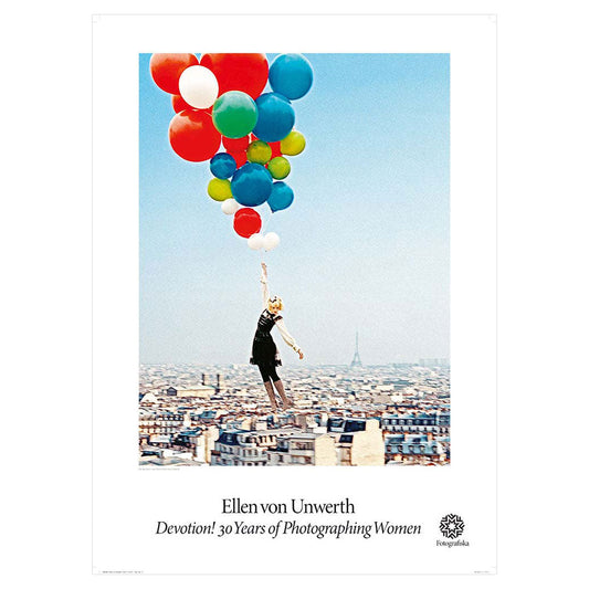 Woman being carried off by helium balloons on clear blue day.  Exhibition title below: Ellen Von Unwerth | Devotion! 30 Years of Photographing Women