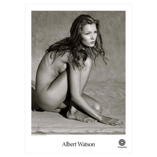 Black and white photo of Kate Moss, nude but sitting on a beach, looking to the distance. Artist name  below: Albert Watson