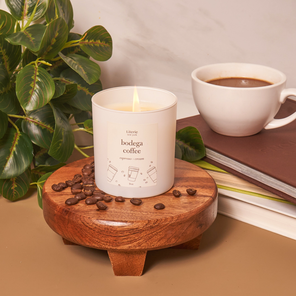 Bodega Coffee Candle, on a coaster surrounded by coffee beans and plants