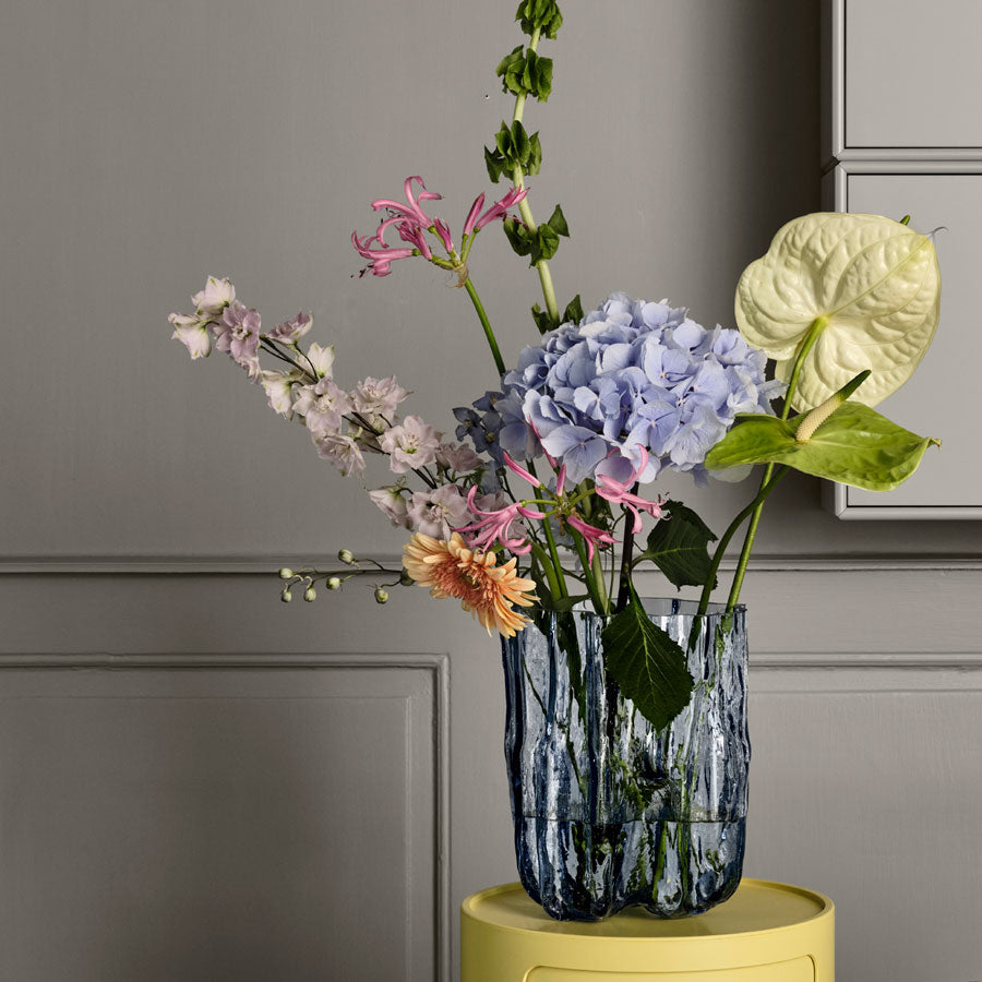 Crackle Vase, Tall Blue, holding a colorful flower arrangement atop a stool in a home lifestyle setting.