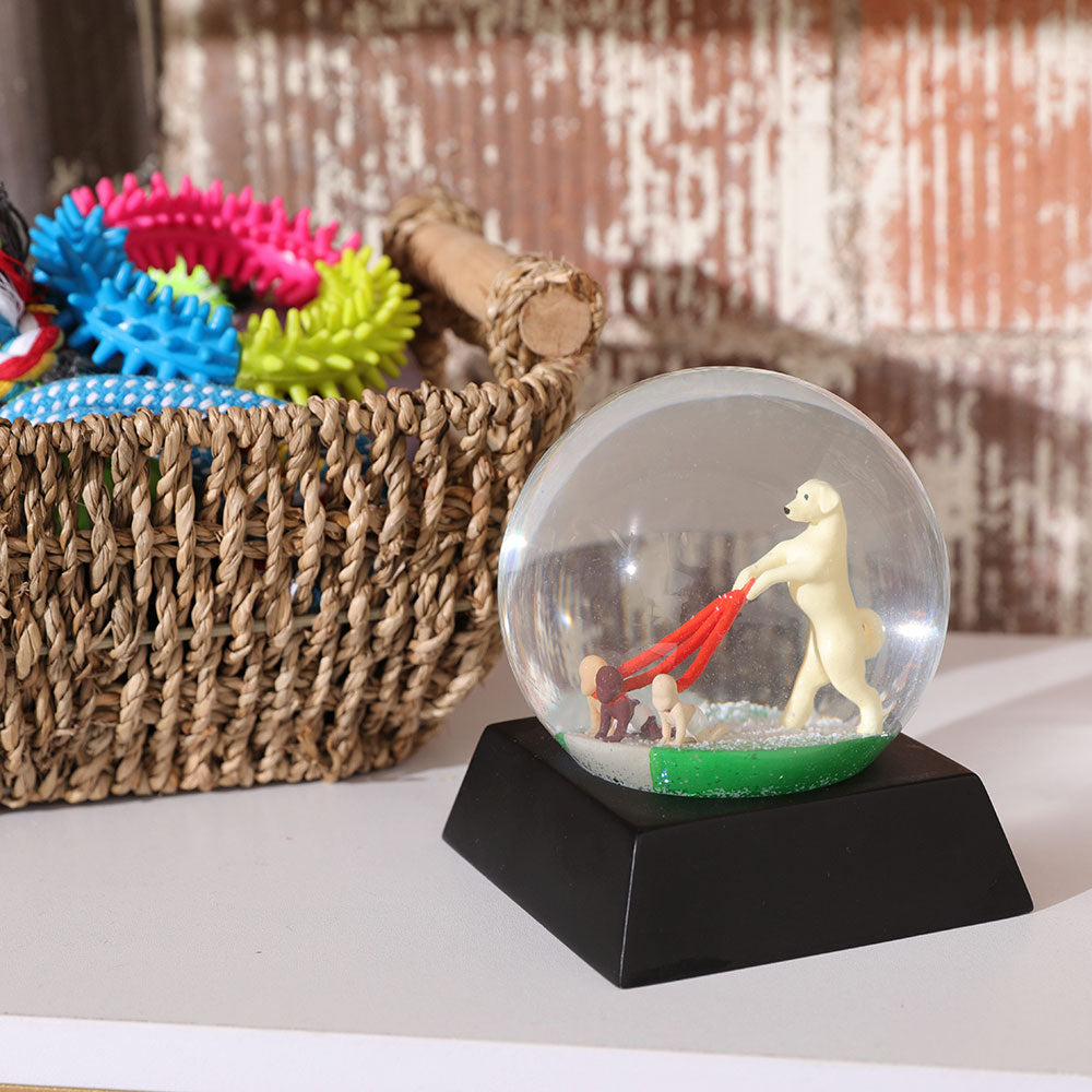 Dog walks snow globe in an our door setting next to a wicker basket