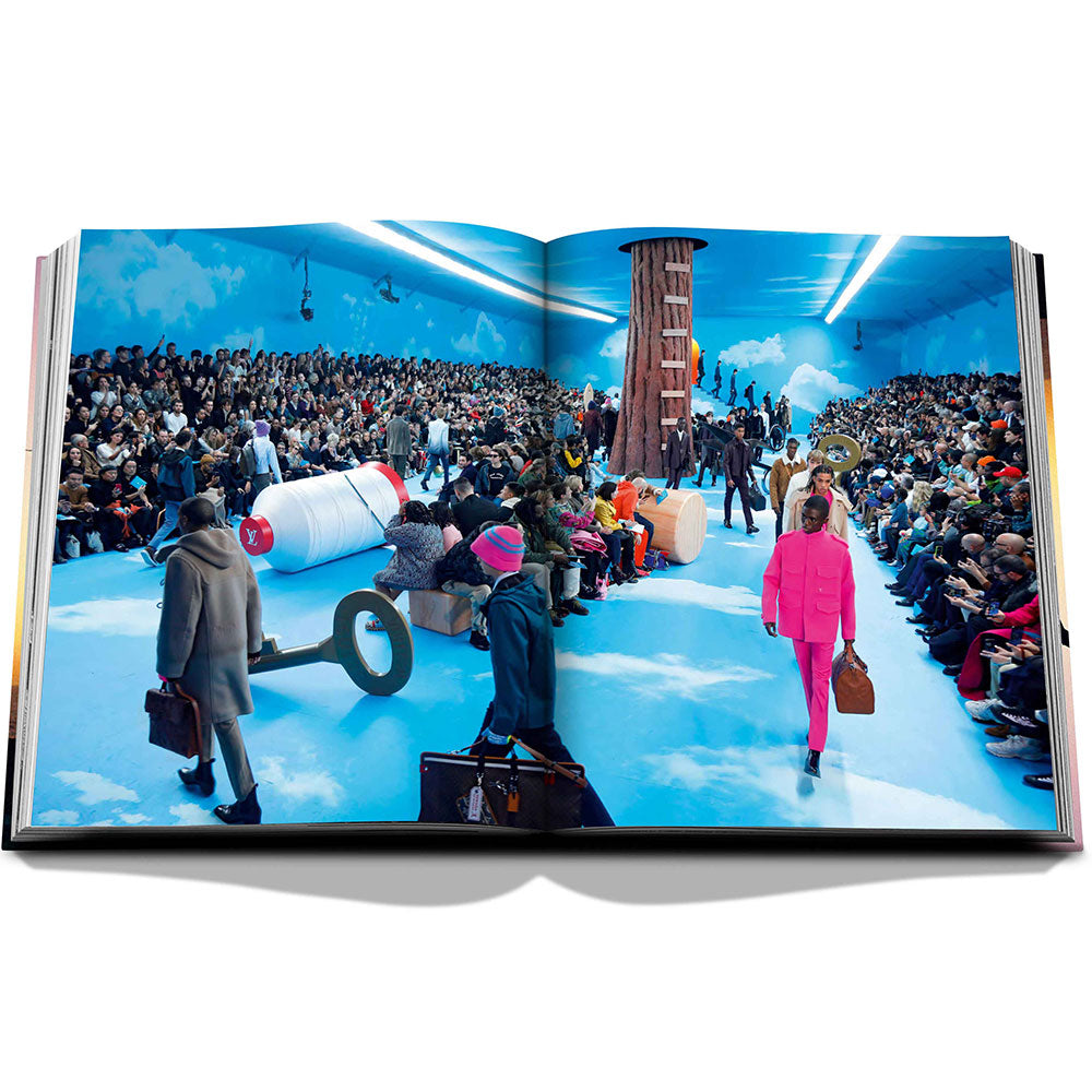 Spread of Louis Vuitton: Virgil Abloh, The Ultimate Collection, showing full-width color image of a fashion models on a runway at a crowded fashion show