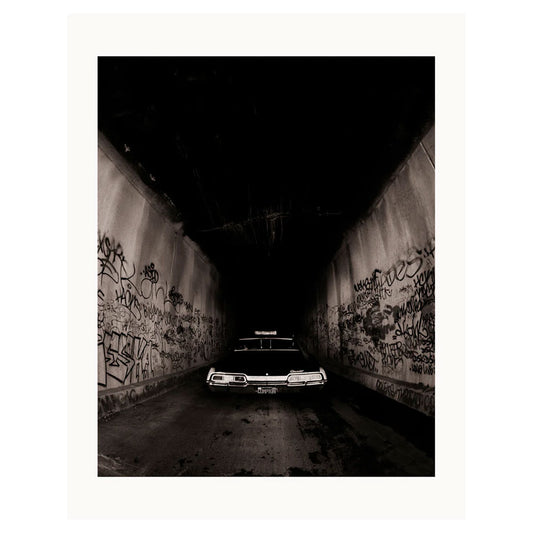 Print of a 1998 album cover for NWA, featuring a flashy black car between two tunnel walls of graffiti.