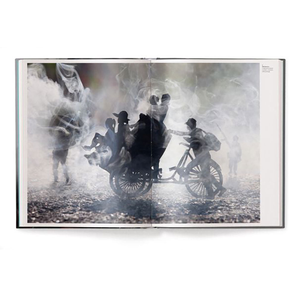 Spread shot of Prix Pictet: Fire, showing full-width black and white photo of bikers in smoke