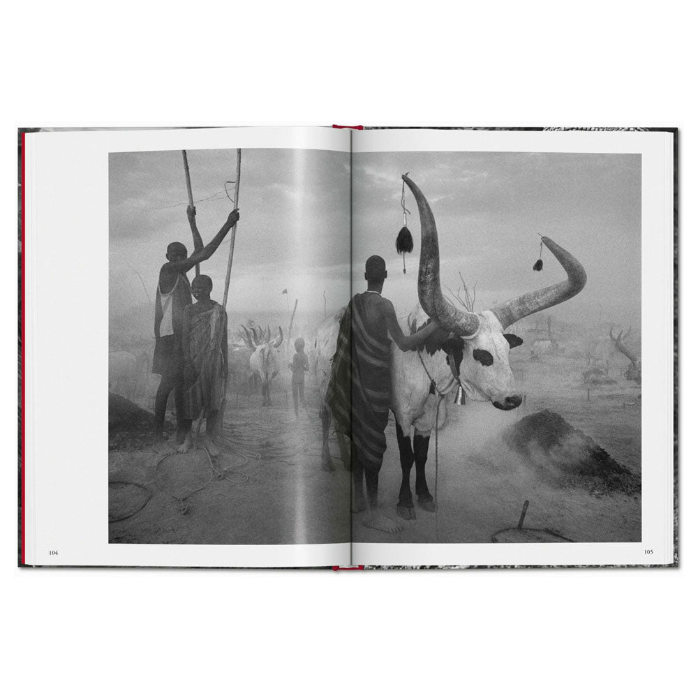 Spread shot of Genesis by Sebastiao Salgado, showing a black and white full-width photo of people with a horned animal.