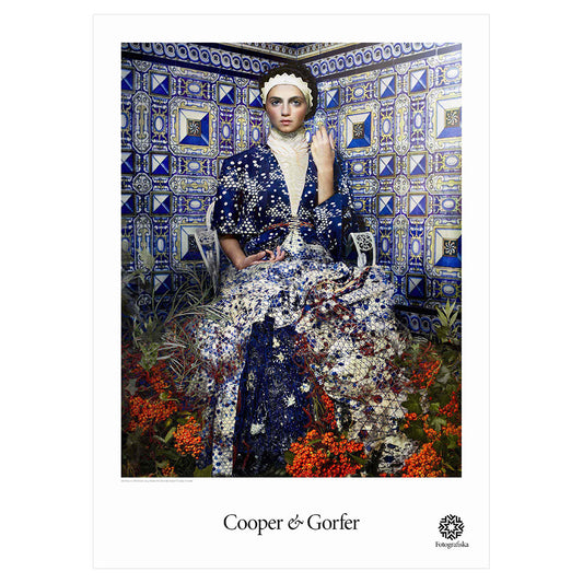 Woman dressed in vibrant outfit in blue titled room. Artist name below: Cooper & Gorfer