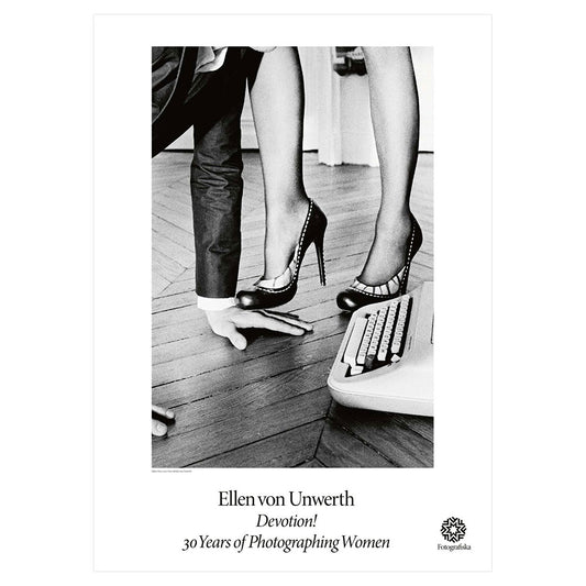 Black and white image of female legs in high heels with a hand of a different person touching the floor.