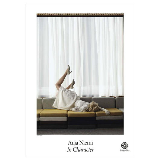 Color portrait of woman lying face down on a couch with her legs in the air. Exhibition title below: Anja Niemi | In Character