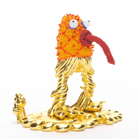 Quirky orange and gold statue of a monster with bugging eyes and tongue sticking out