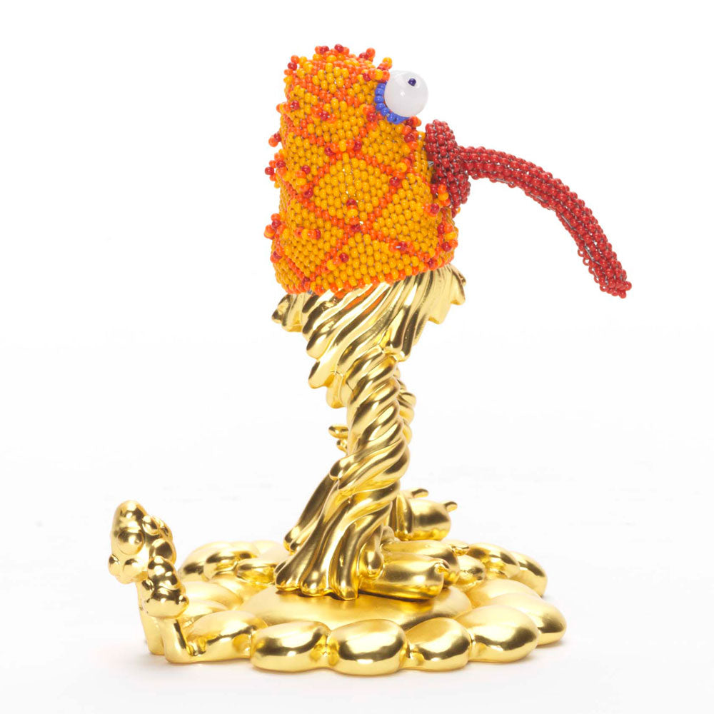 Quirky orange and gold statue of a monster with bugging eyes and tongue sticking out, turned right