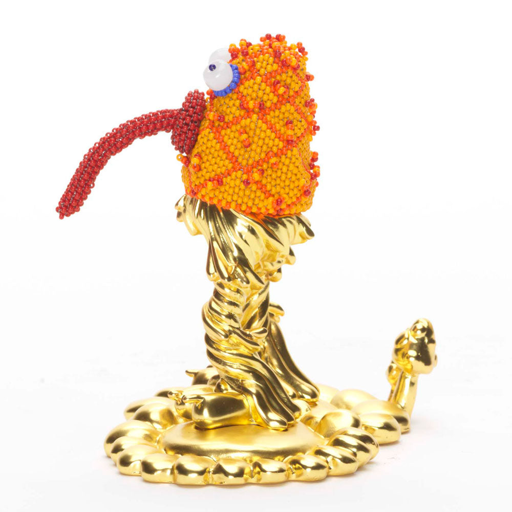 Quirky orange and gold statue of a monster with bugging eyes and tongue sticking out, facing left