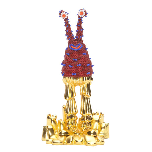 Quirky burgundy and gold statue of a monster with eyes high above head.