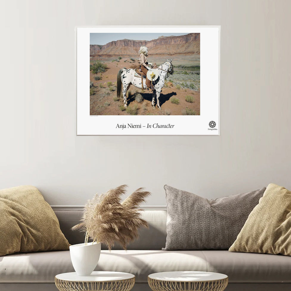 The Imaginary Cowboy poster framed on a beige wall above a couch and coffee tables.