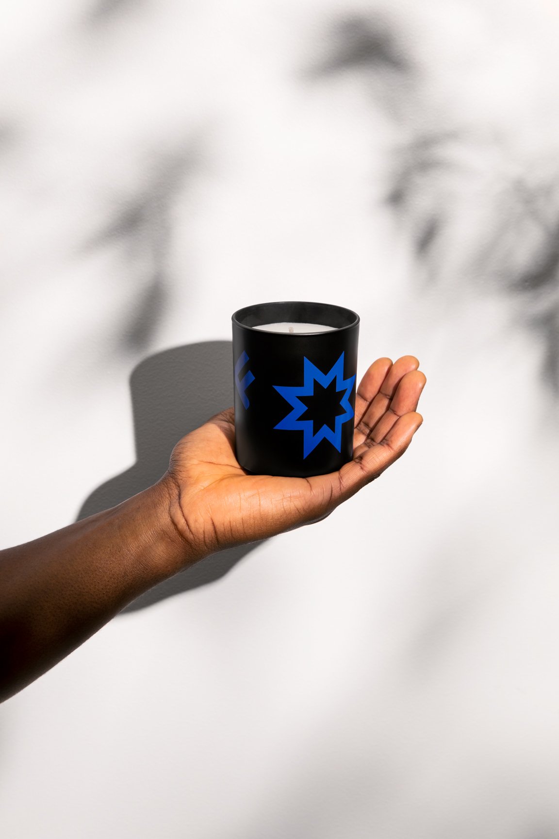 One hand holding the black Perspectives candles.