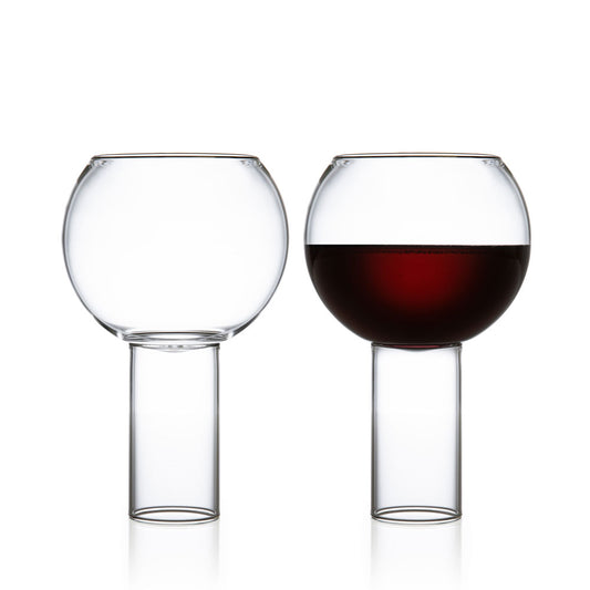 Set of 2 tall large glasses, one empty and one with liquor.