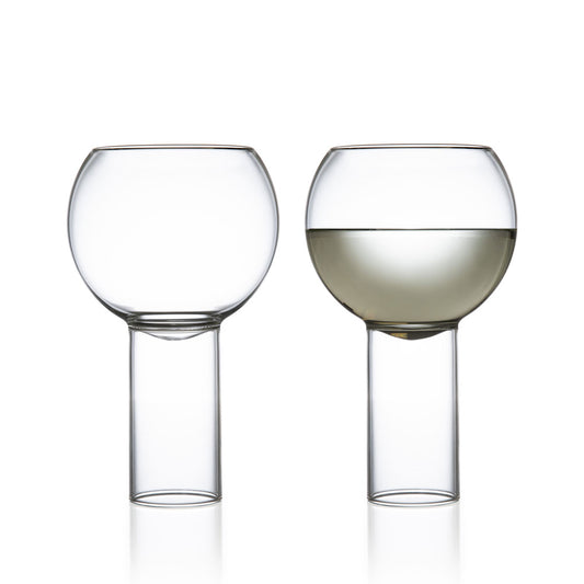 Set of two tall medium drinking glasses, one empty and one filled with liquor