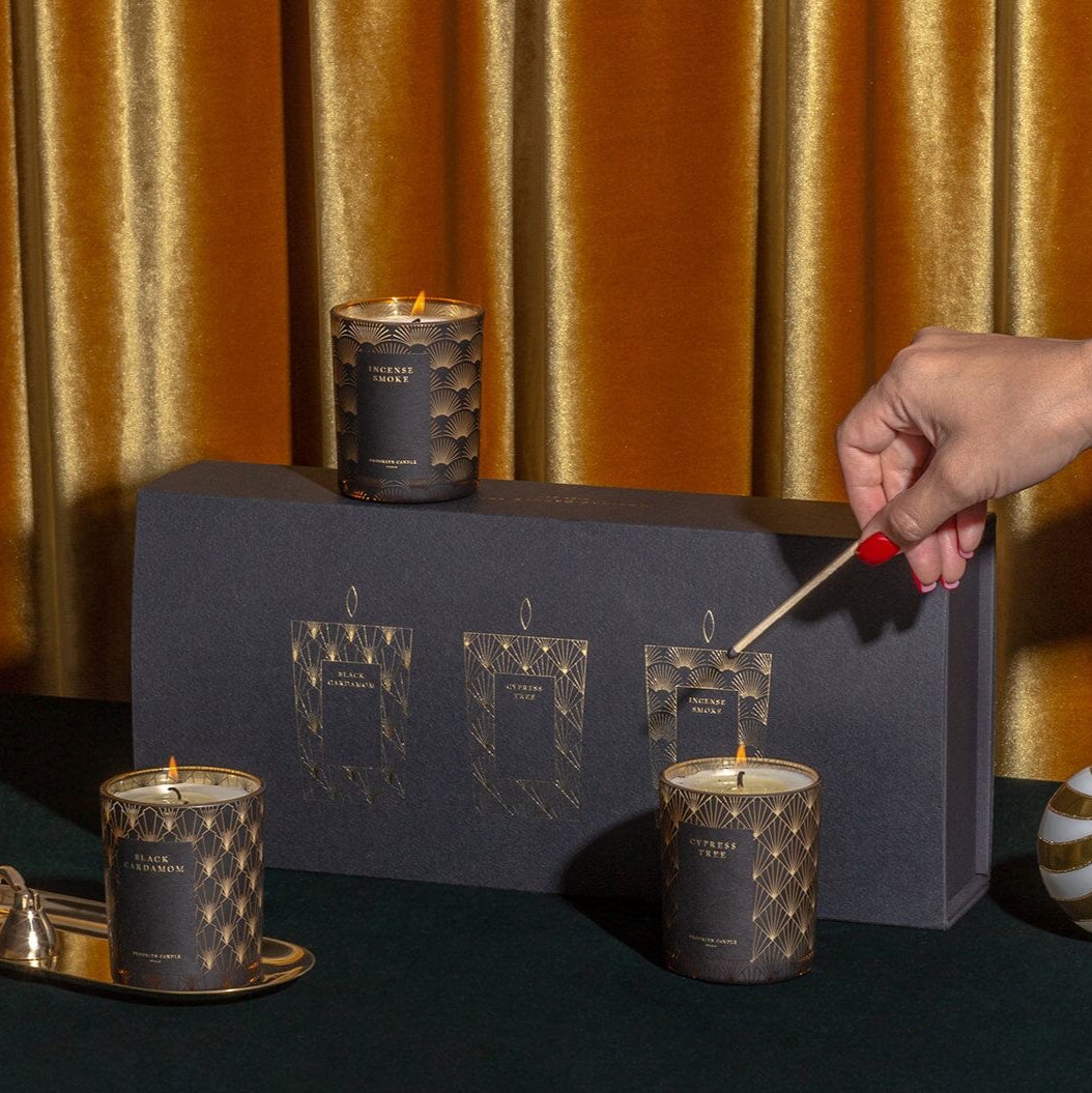 Black Tie Holiday Candle Trio Gift Set, being lit by a hand.