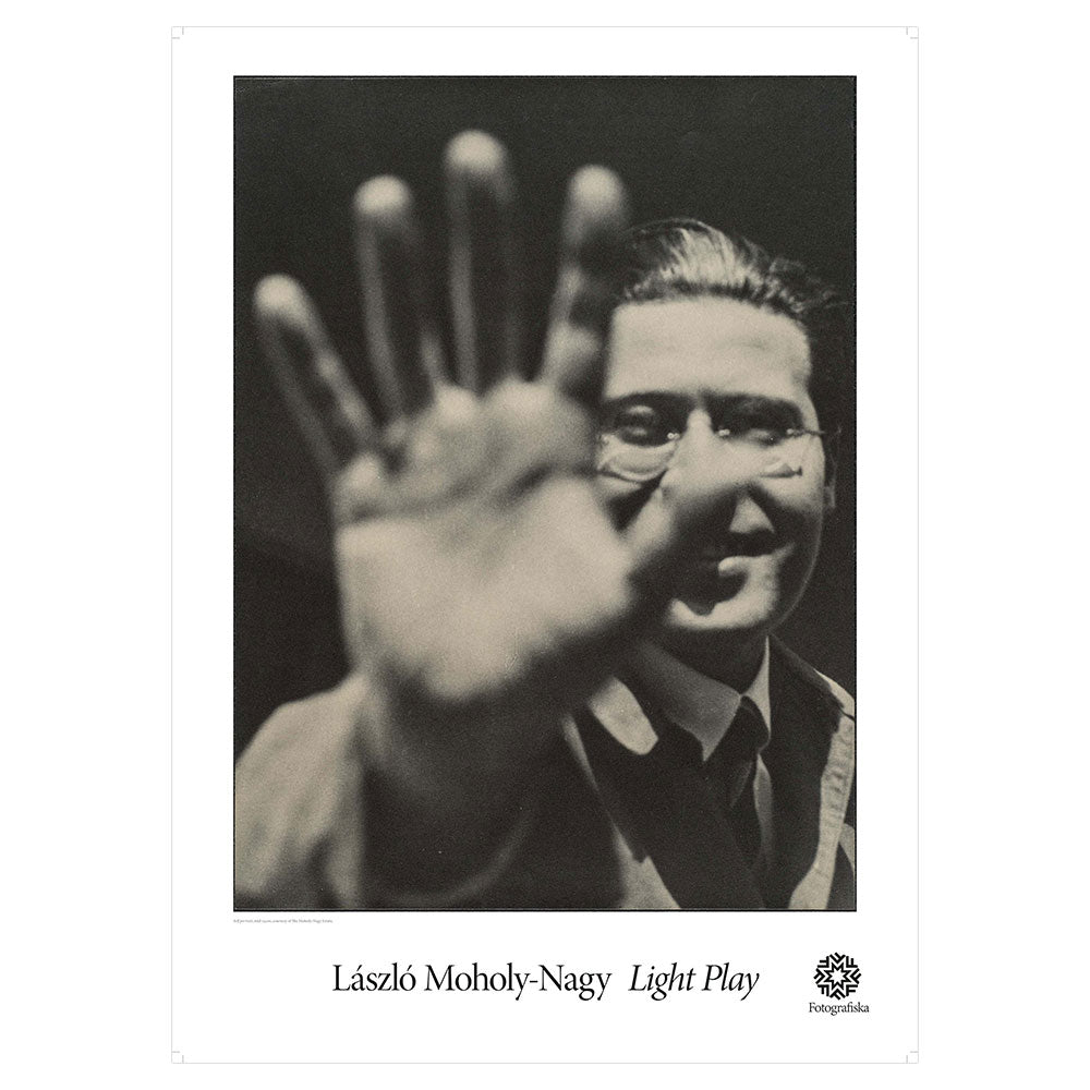 Laszlo Moholy Nagy with smile on his face holding open hand up to the viewer, partially blocking his face. Exhibition title below: Laszlo Moholy-Nagy | Light Play