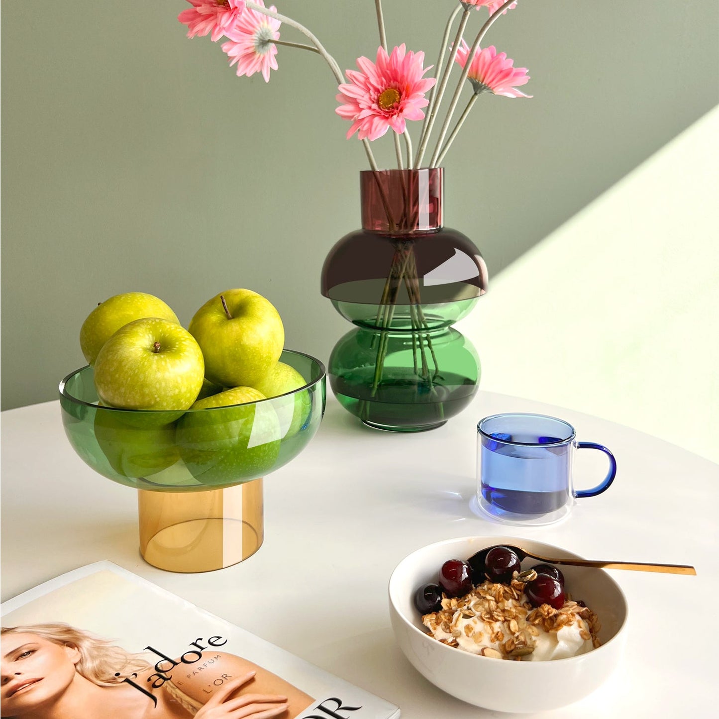 Tip Top Glass Bowl by Cloudnola, in green and yellow, shown holding apples on a colorful table.