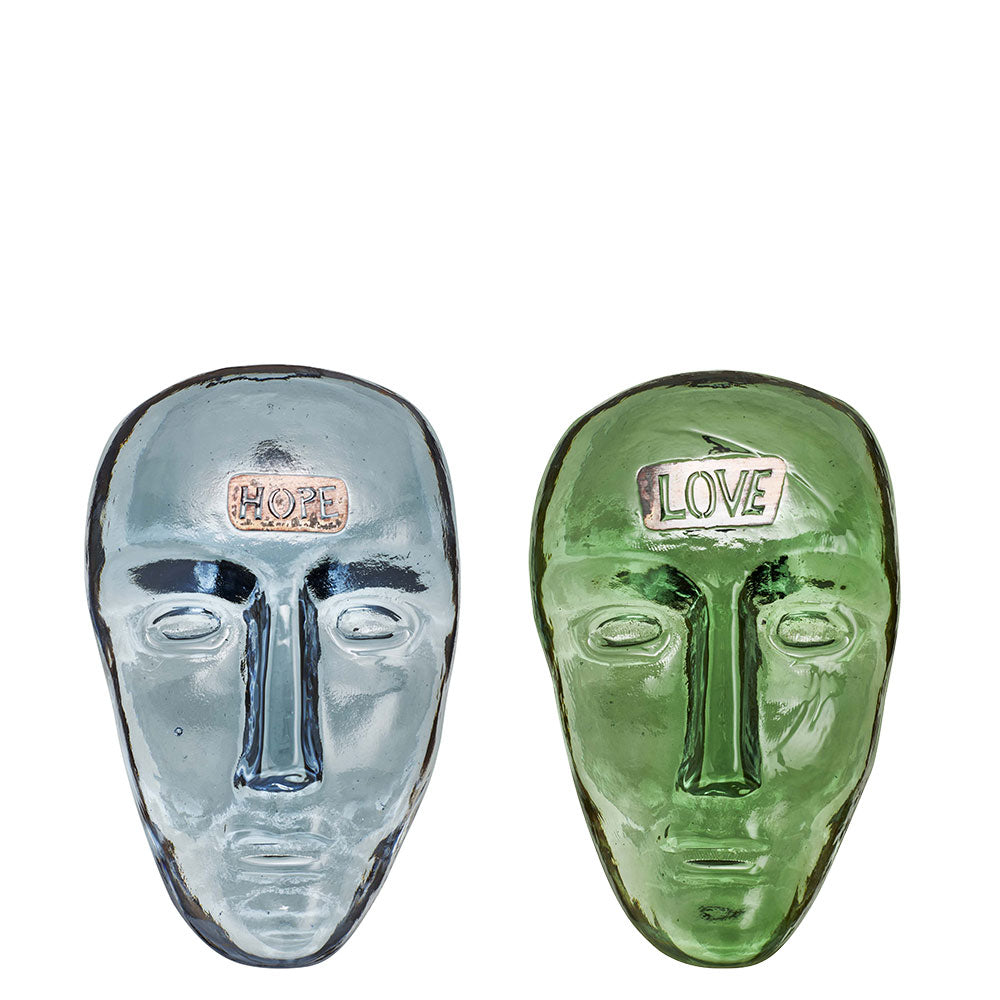 Blue glass face with the word "Hope" on the forehead next to a green glass face with the word "Love" written on the forehead. Designed by Bertil Valien.