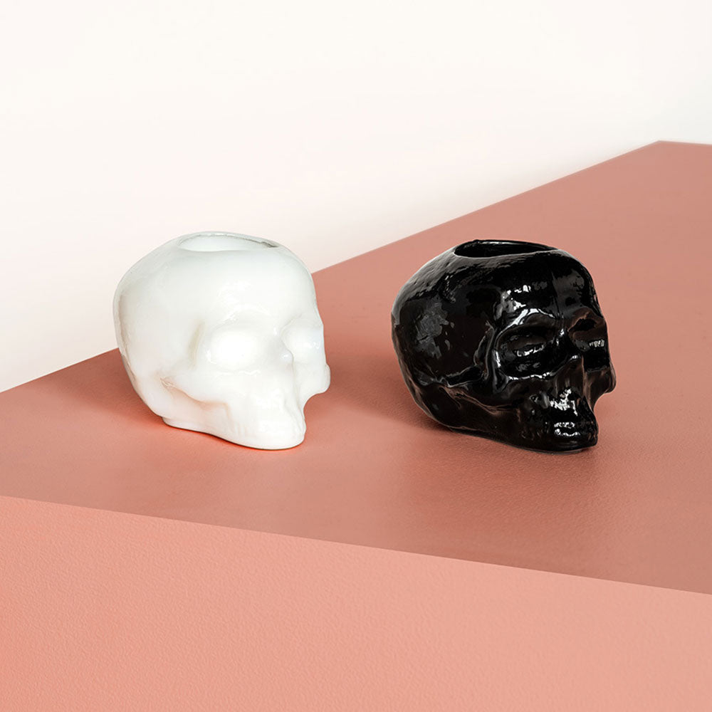 Black Glass Skull candleholder next to a white skull candleholder