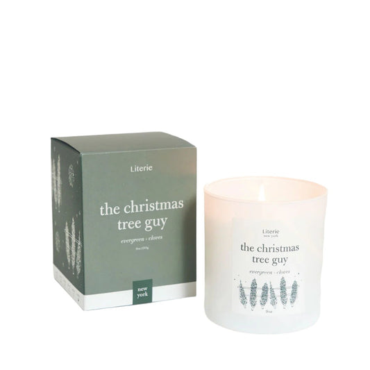 The Christmas Tree Guy Candle candle by Literie - notes of evergreen and cloves, shown next to its packaging.