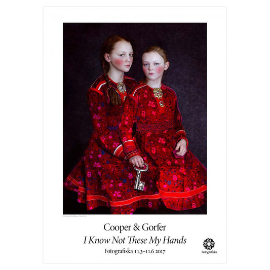 Color portrait of two girls with rosy cheeks in red dresses. Exhibition title below: Cooper & Gorfer | I Know Not These My Hands
