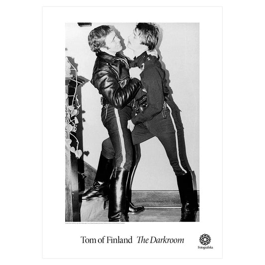 Black and white portrait of two men in playful embrace. Exhibition title below: Tom of Finland | The Darkroom
