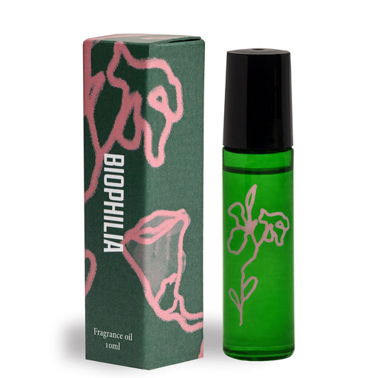 Green perfume bottle with black cap next to beautiful floral packaging with Biophilia on the label