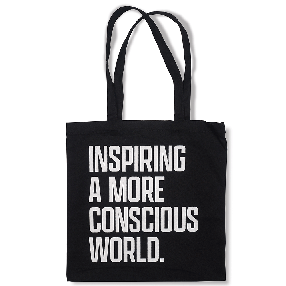 Black tote bag with "Inspiring a more conscious world" written in white.