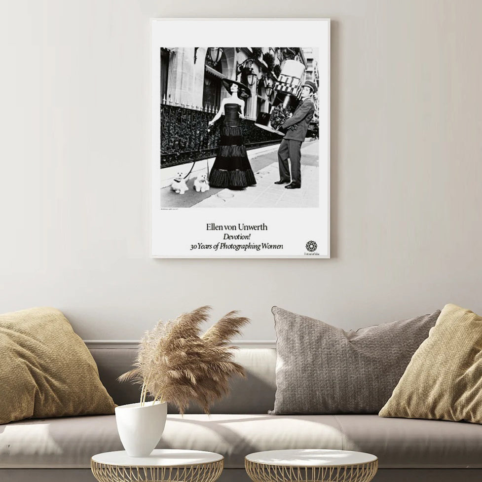 Rich Bitch poster framed on beige wall of living room above a couch and coffee tables.