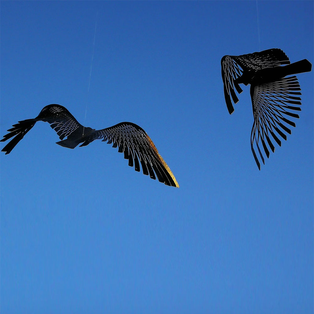 Black birds mobile against blue sky