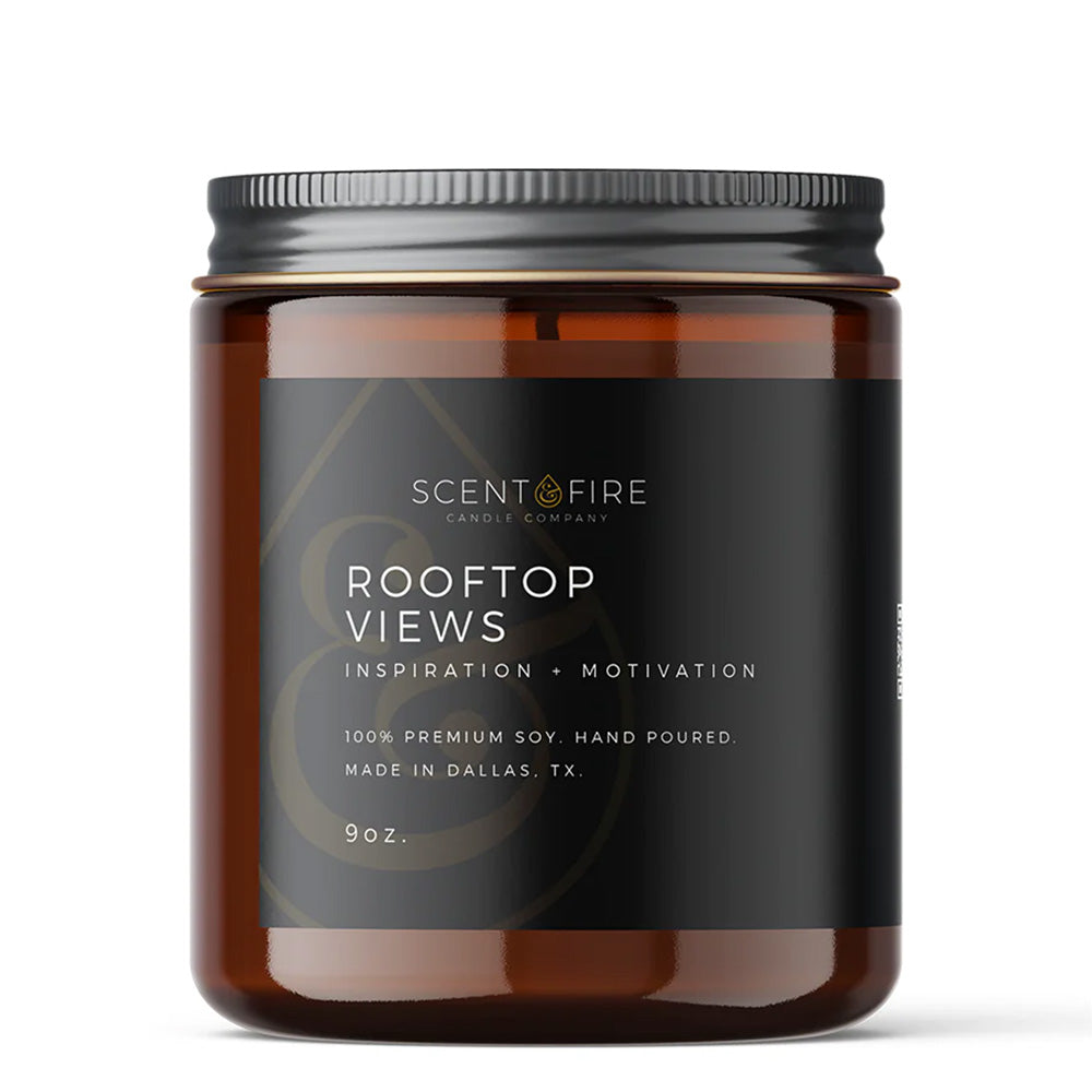 Candle jar with Scent & Fire Label, with the name "Rooftop Views" and writing underneath: Inspiration, Relaxation, 100% Premium Soy, Hand-poured, Made in Dallas, TX, 9 ounces